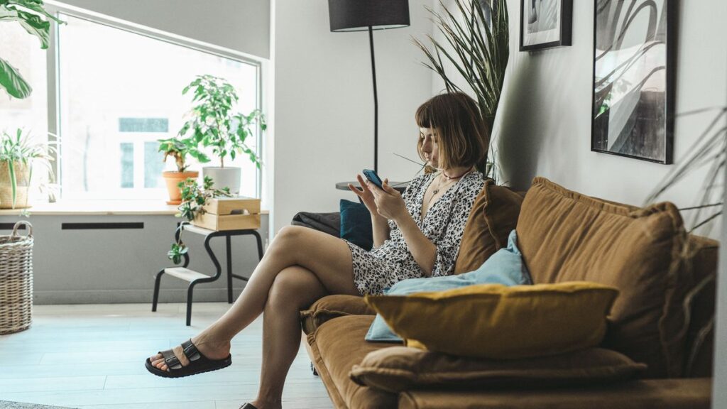 Chatbot de WhatsApp para inmobiliarias: clienta escribiendo a una agencia desde el sofá